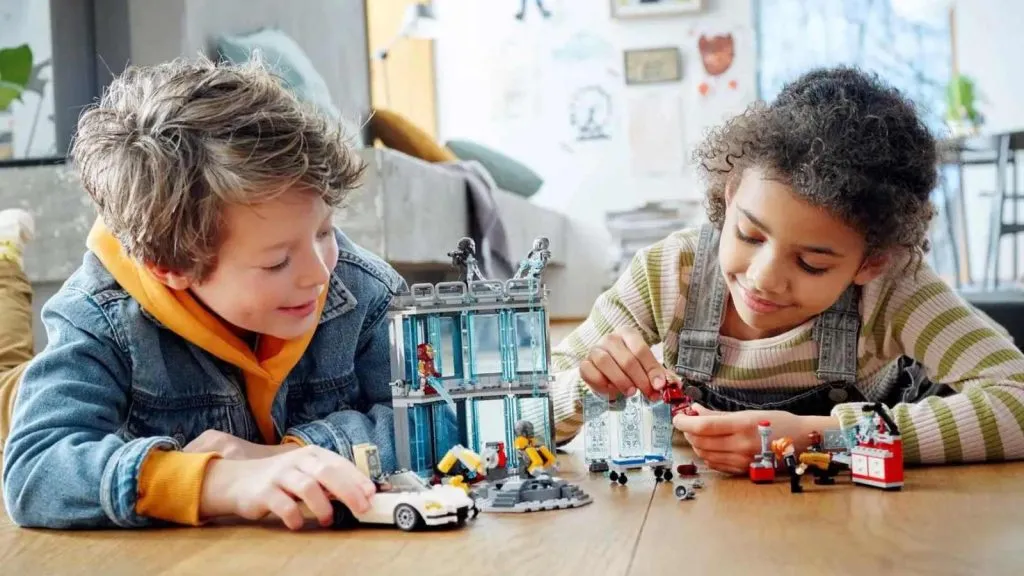 Deux enfants jouant avec l'ensemble LEGO Marvel Iron Man Armory.