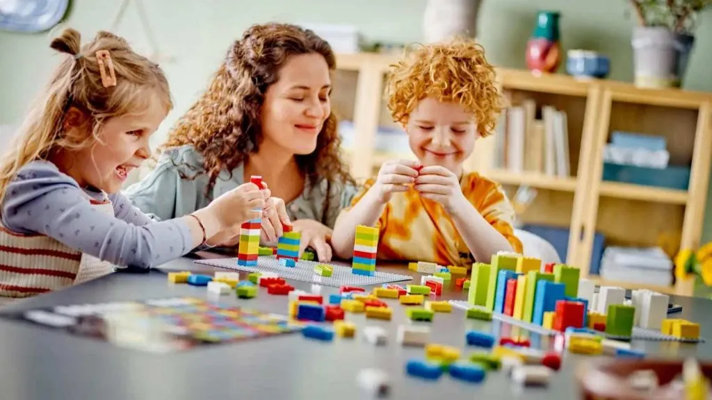 Um adulto e crianças brincando com seus blocos LEGO Braille