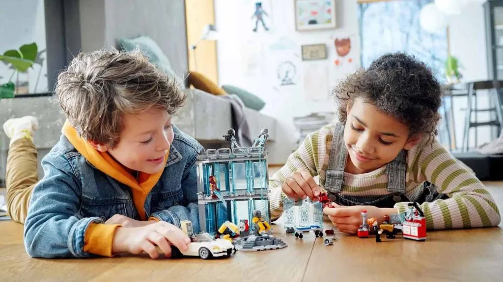 Deux enfants jouant avec leur ensemble LEGO Marvel Iron Man Armory.