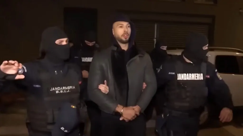 Andrew Tate w czarnej kurtce przetrzymywany przez policję