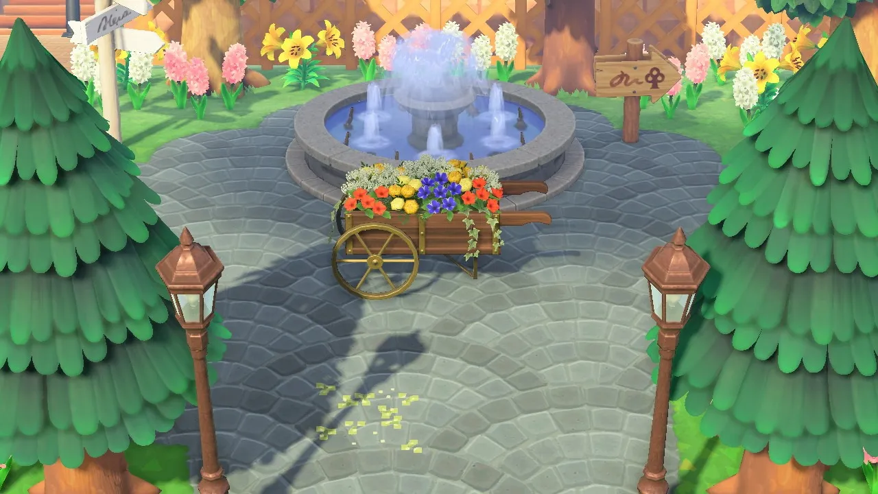 Une image d'une partie d'un aménagement d'Animal Crossing Island comportant une fontaine, des arbres, des fleurs et des lampadaires.