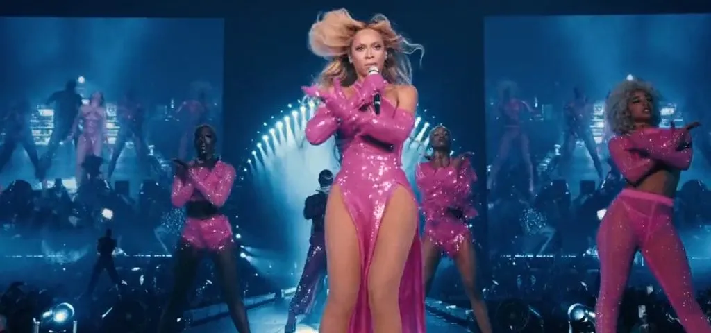 Beyonce actúa con un vestido rosa en el escenario de un concierto.