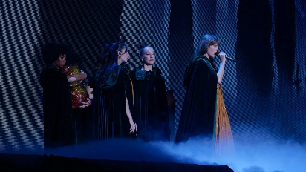 Taylor Swift portant une cape noire et se produisant sur scène lors de sa tournée Eras