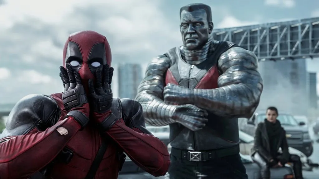 Deadpool y Colossus parados en un puente en la película Deadpool, con las manos de Deadpool sobre su rostro.