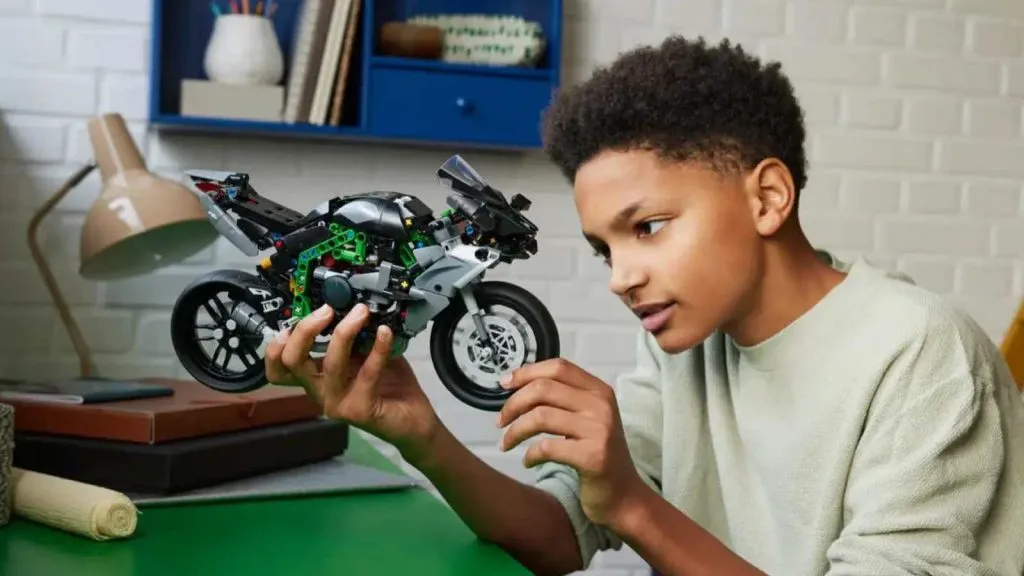 Un niño admirando su set de motocicleta LEGO Technic Kawasaki Ninja H2R