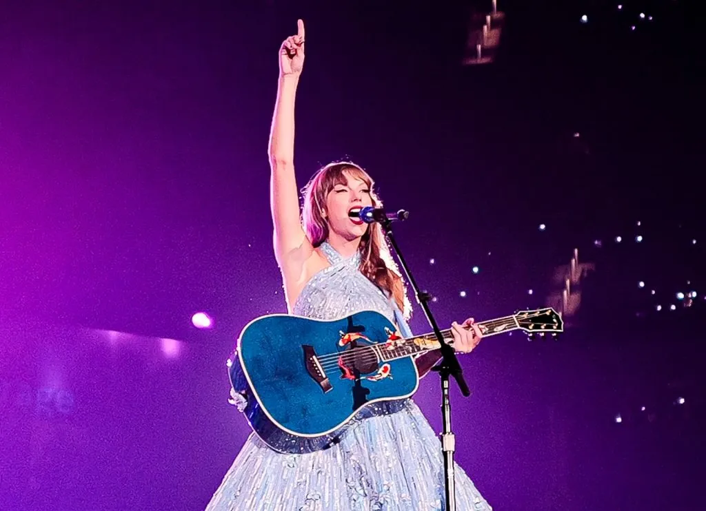 Eras Tour 콘서트 무대에서 청록색 기타를 연주하고 있는 Taylor Swift