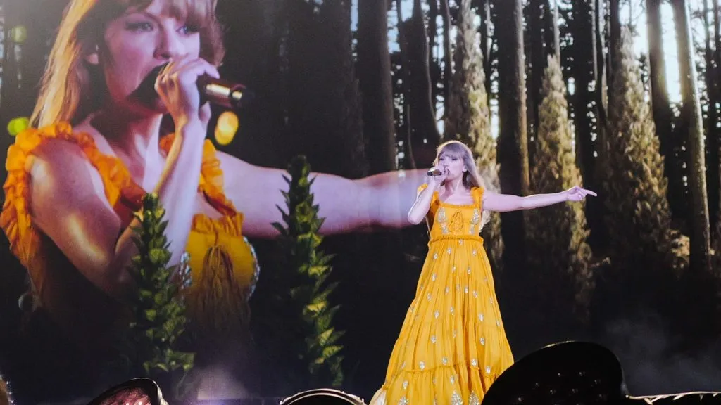 Erasツアー中にステージ上でパフォーマンスを披露する黄色いドレスを着たテイラー・スウィフト