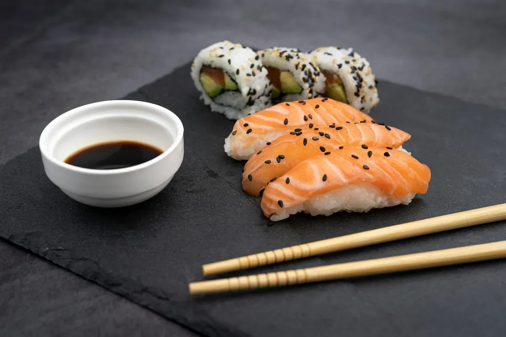 Un plato de sushi y nigiri con palillos.