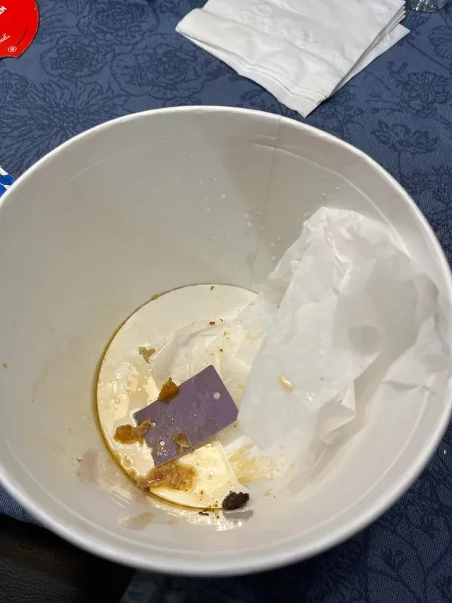 一張空肯德基桶的照片，裡面有一張紫色卡片。