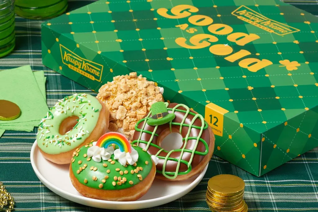 Uma foto de quatro donuts temáticos do Dia de São Patrício com uma caixa verde no fundo