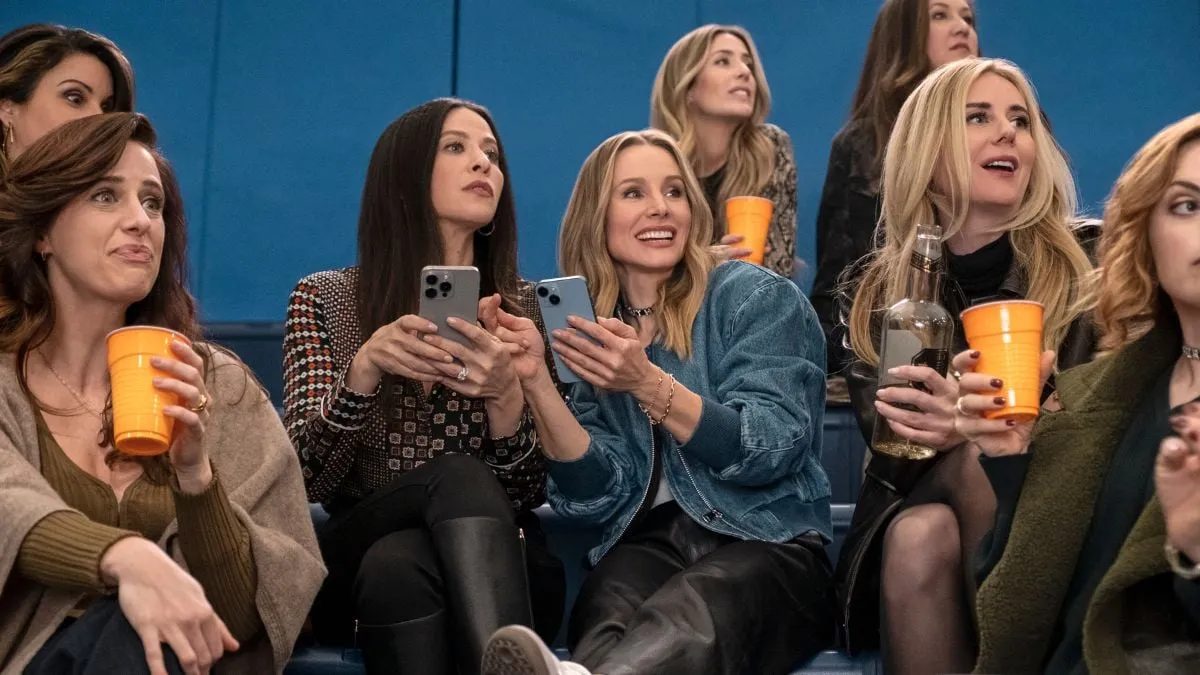 Jackie Tohn as Esther, Kristen Bell as Joanne, Justine Lupe as Morgan watch a basketball match with drinks in Nobody Wants This