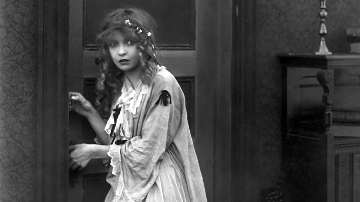 A woman cautiously walking down a hallway in