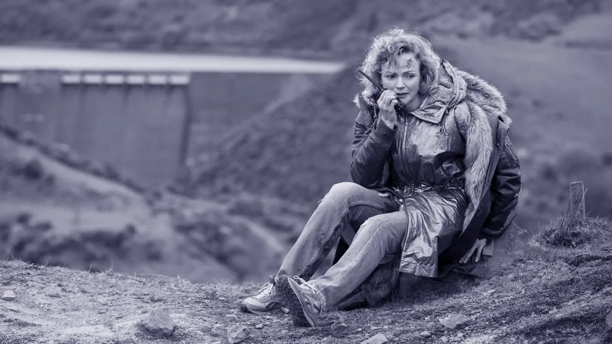 A woman holds a walkie-talkie, deep in thought