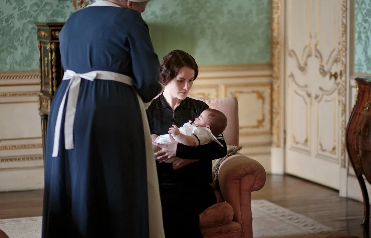 Lady Mary segurando seu bebê com uma enfermeira ao lado dela