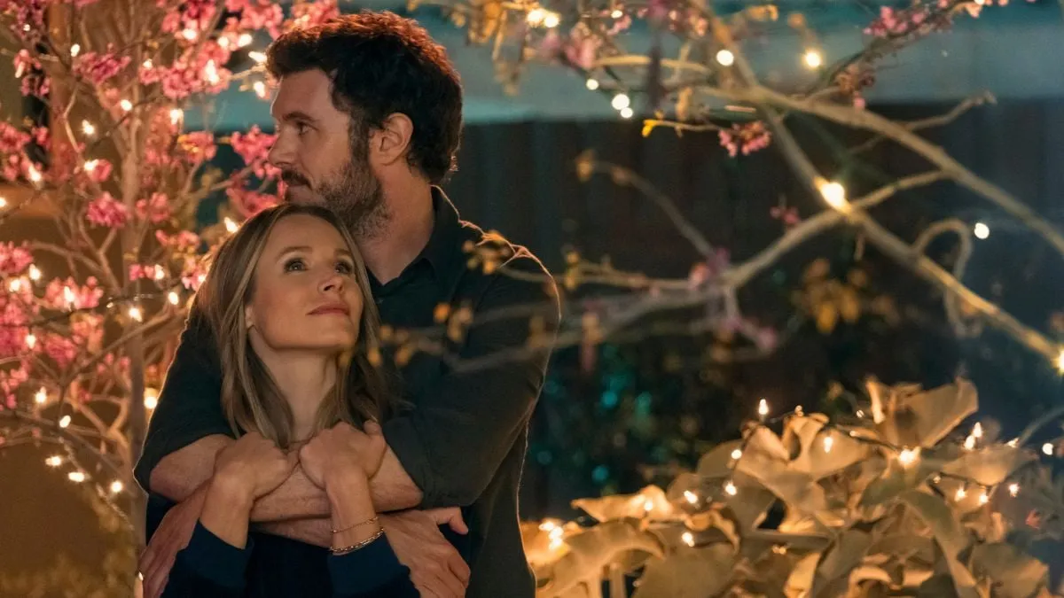 Adam Brody, como el rabino sexy Noah Roklov, rodea con su brazo a Joanne (Kristen Bell) desde atrás en una escena de Nobody Wants This en Netflix