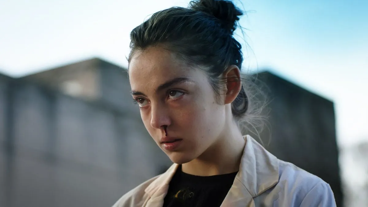 A young woman stares ominously with a bloody nose in