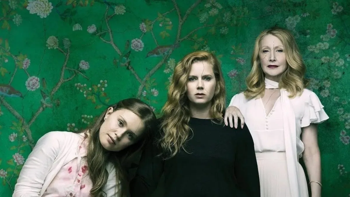 Three women pose against a green background in promotional art for 'Sharp Objects'