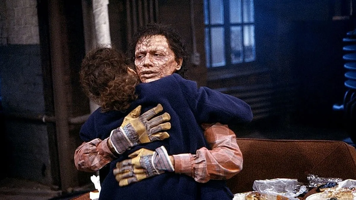 A mutated man embraces a woman on a living room floor in