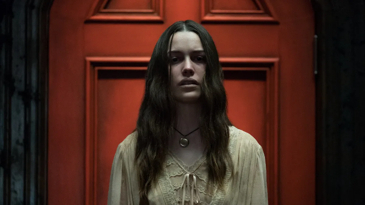 Une femme se tient devant une porte rouge effrayante dans « The Haunting of Hill House »