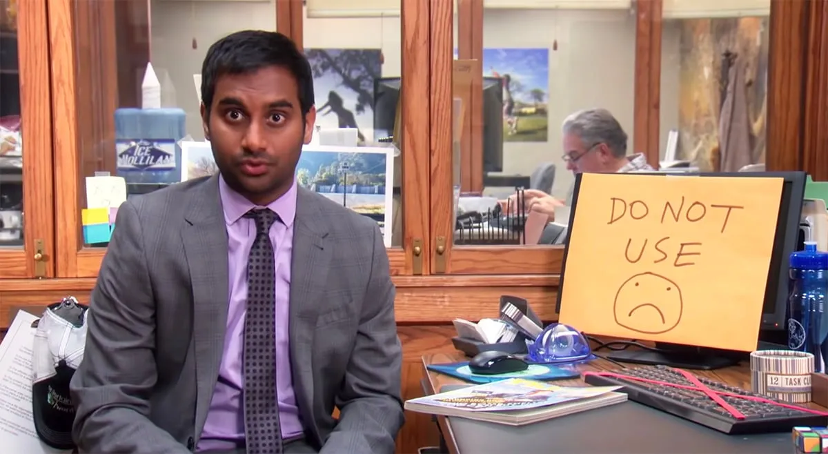 Tom Haverford siedzi przed komputerem, na którym widnieje napis