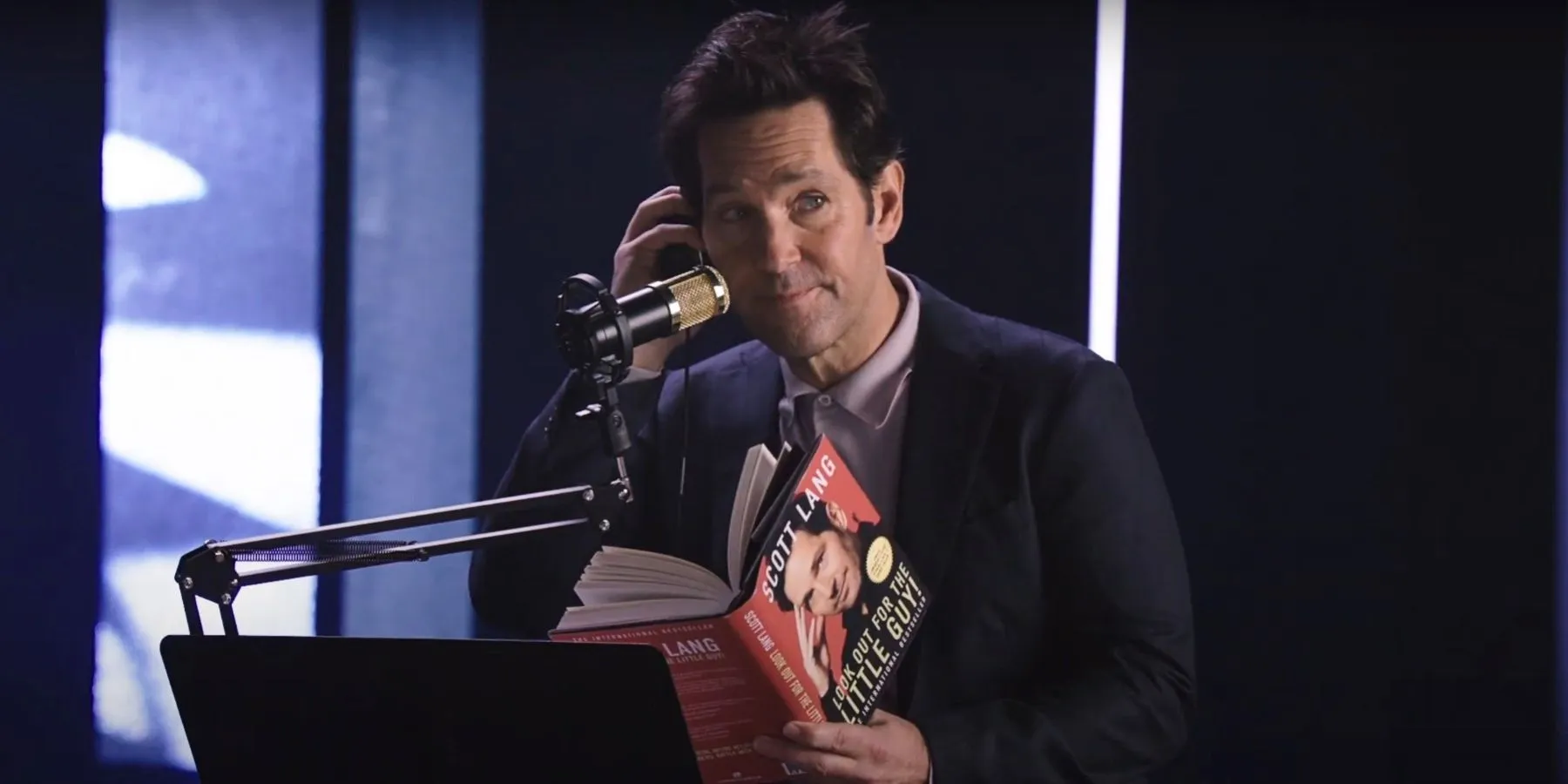 Paul Rudd reading Ant-Man book in front of a microphone