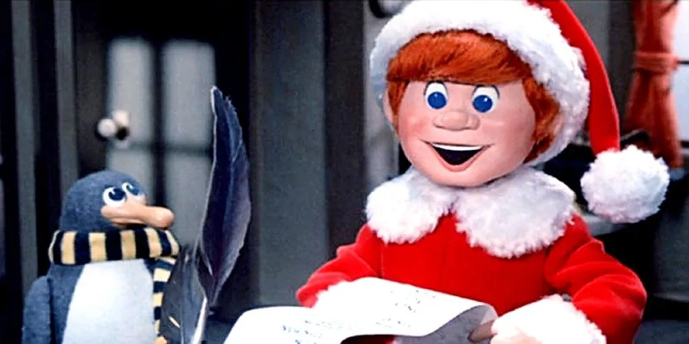 Kris Kringle als junger Mann, der eine Liste mit einem Pinguin liest in Santa Claus is Comin to town