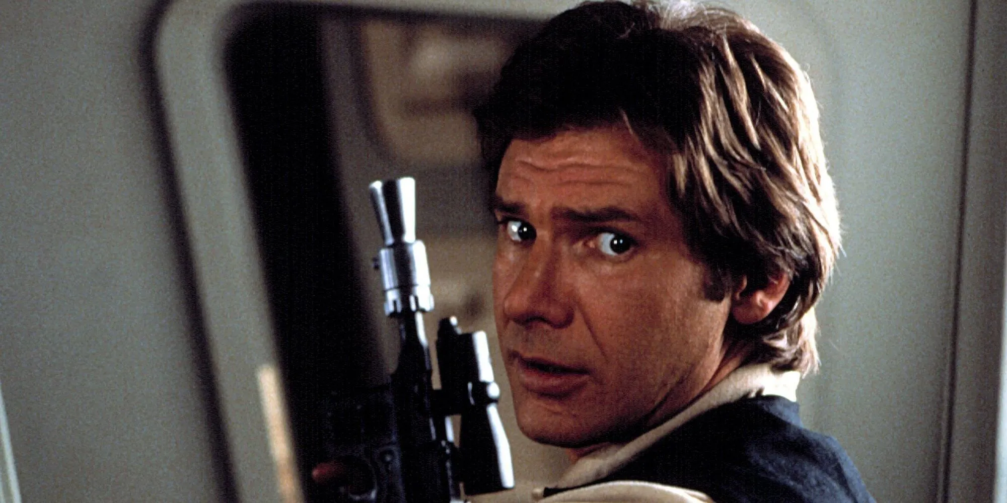 Harrison Ford als Han Solo in Star Wars hält einen Blaster und blickt von hinten und von der Seite in die Kamera