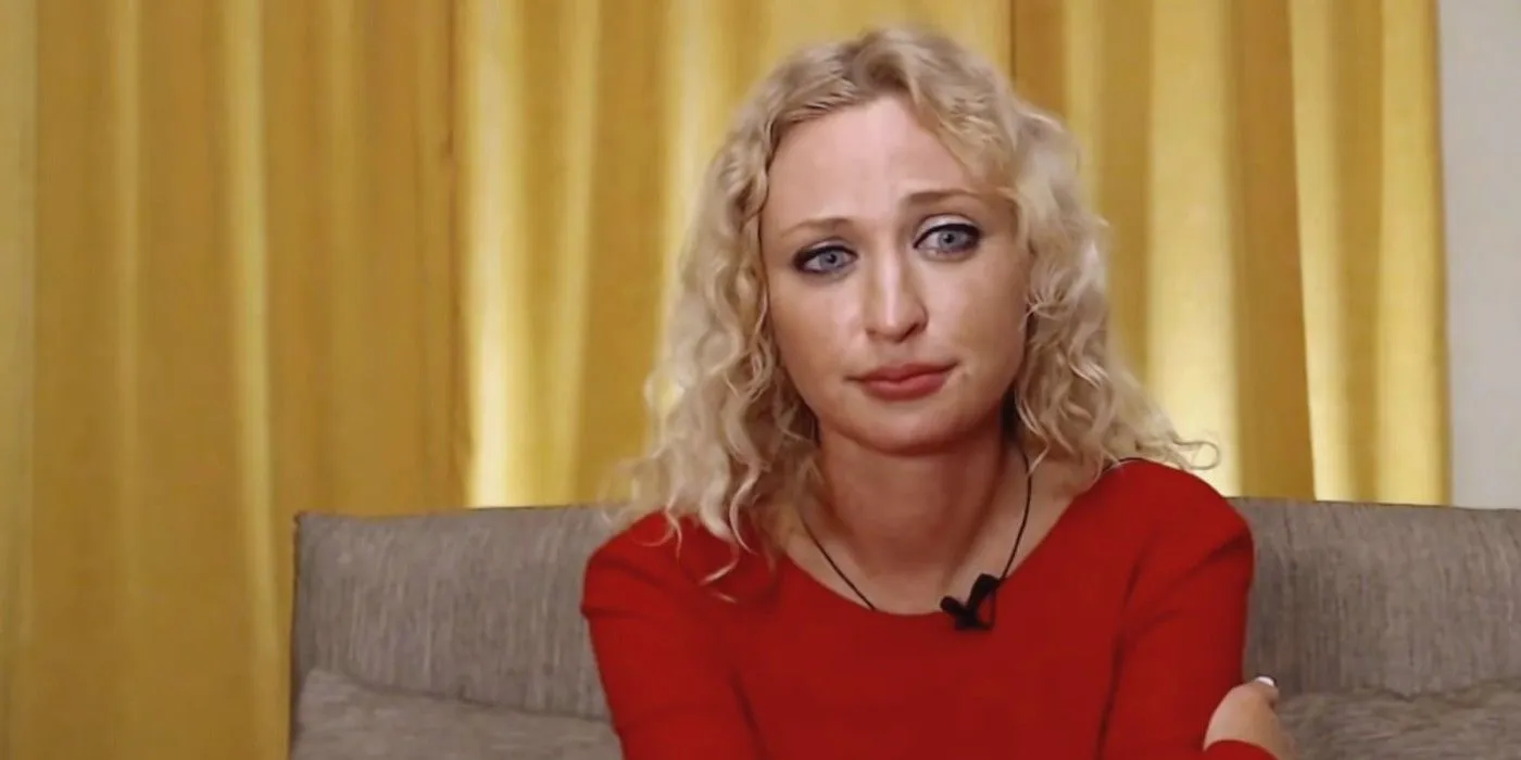 Natalie Mordovtseva dans 90 Day Fiance 6 en robe rouge en pleurs assise sur le canapé