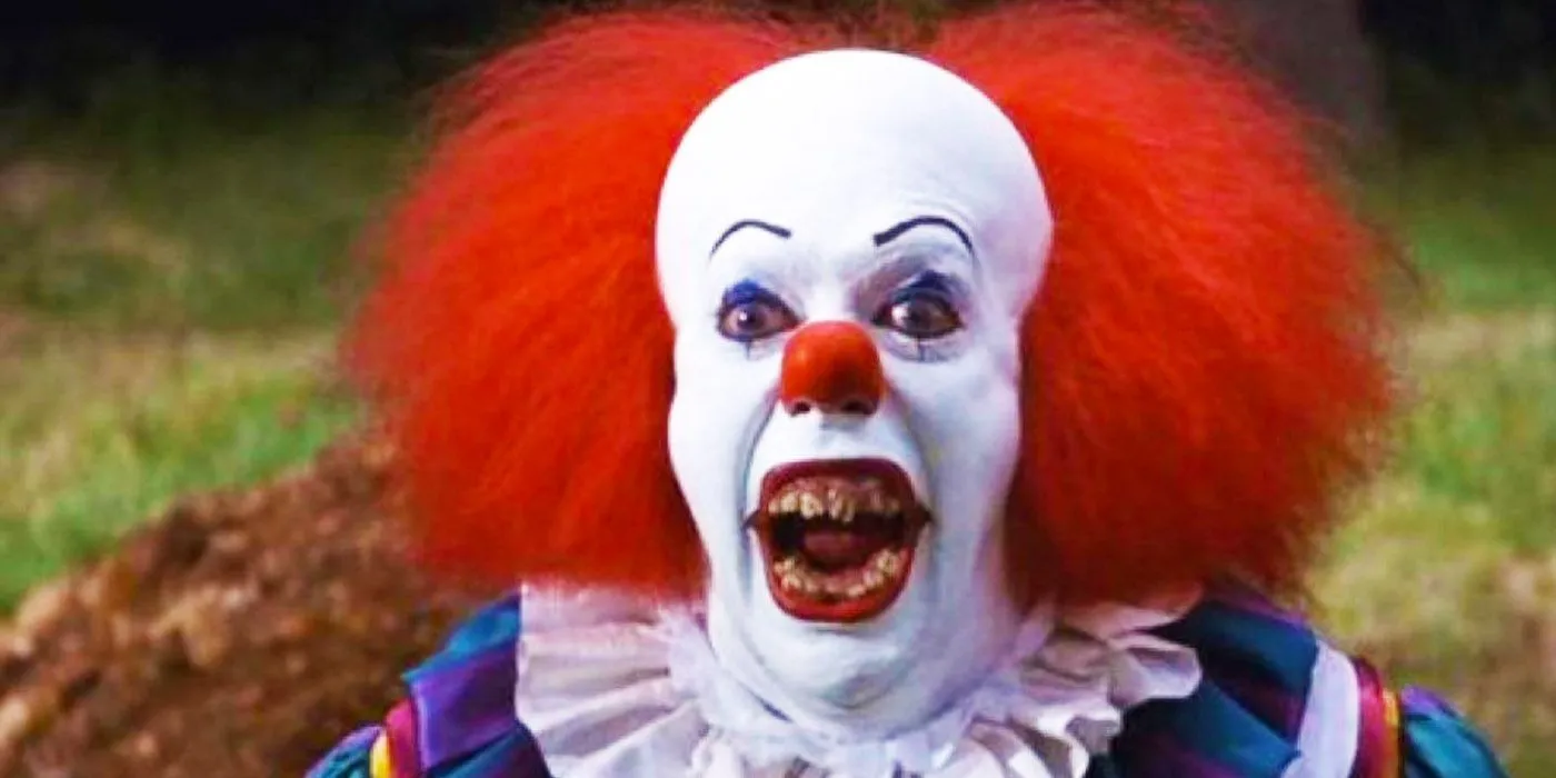 Tim Curry como Pennywise mostrando los dientes en la miniserie IT