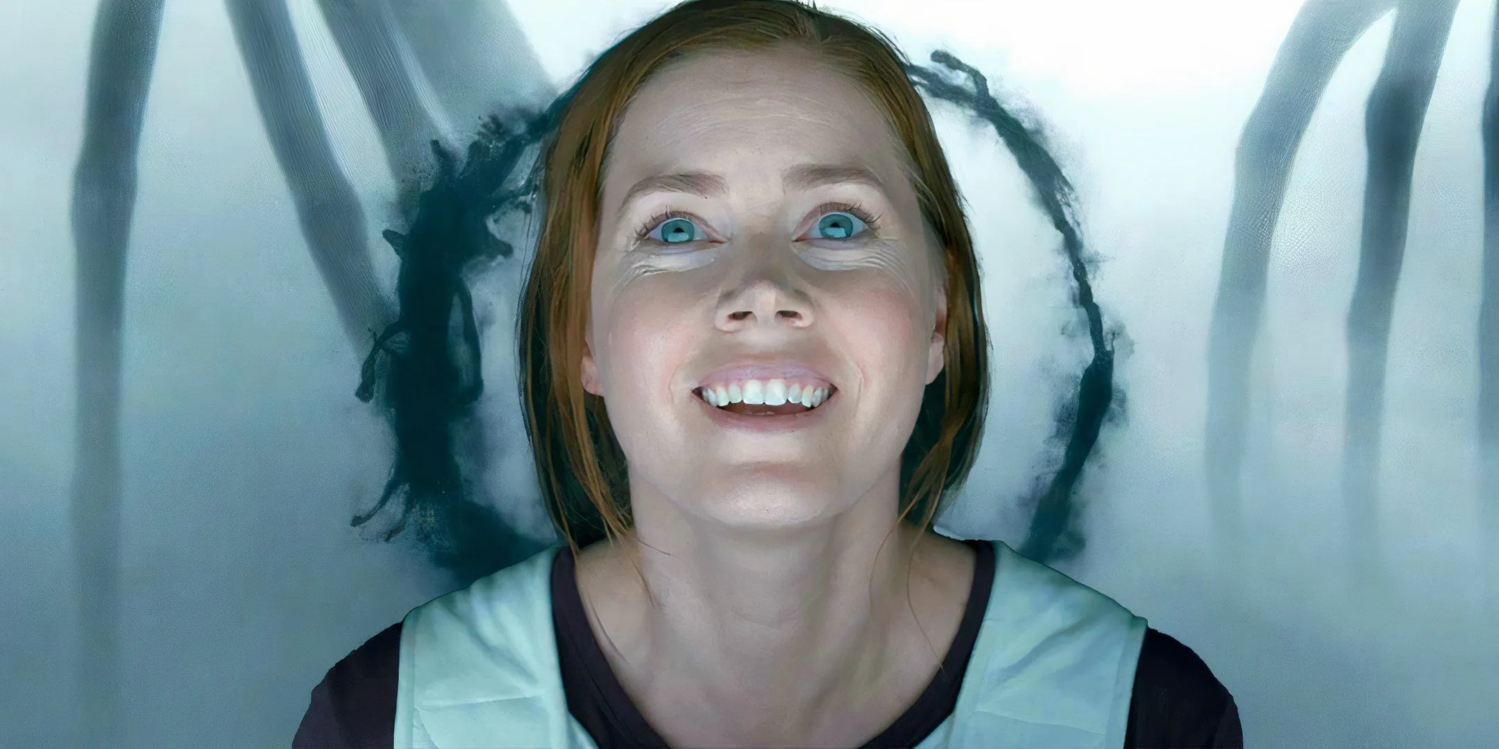 Amy Adams nei panni di Louise sorride sullo sfondo di un linguaggio alieno in Arrival