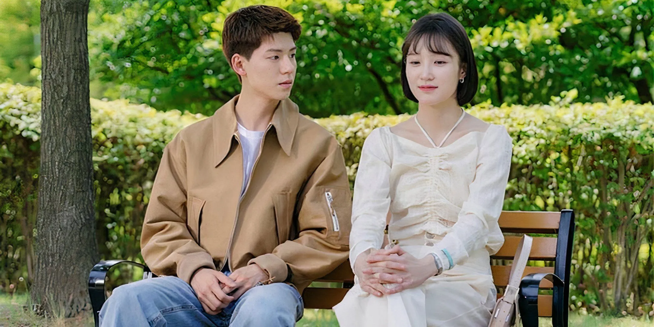 Bae Hyun-sung and Seo Ji-hye sit on a bench together outside.