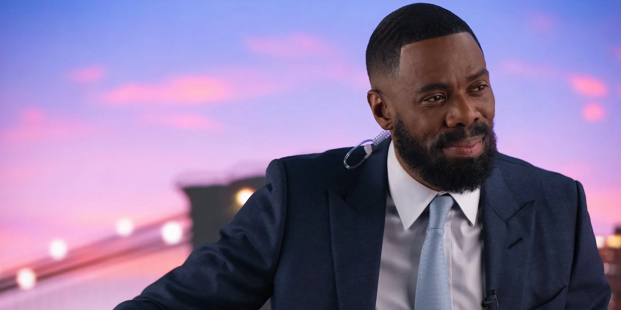 Colman Domingo dans le rôle de Muncie souriant assis à un bureau de diffusion de CNN dans The Madness