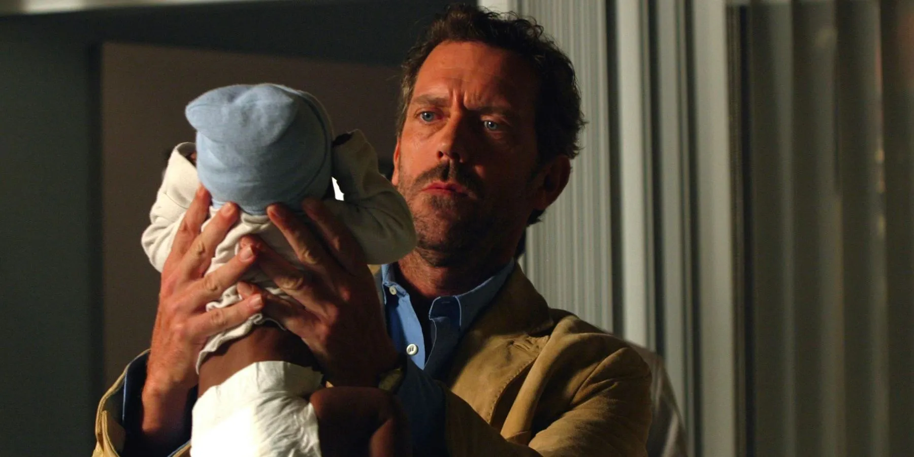 Le Dr Gregory House (Hugh Laurie) tient un bébé dans la maternité de la saison 1, épisode 4