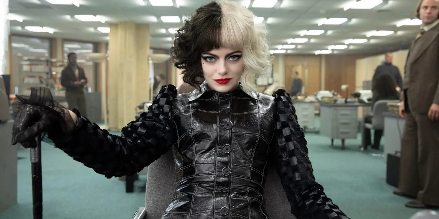 Emma Stone como Cruella sonríe en una oficina con un bastón en Cruella