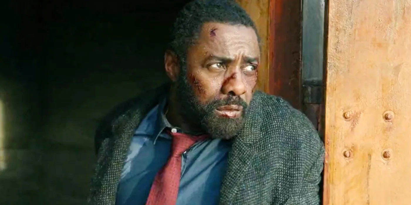 Luther (Idris Elba) looking battered and beat up while hiding behind a wall in Luther