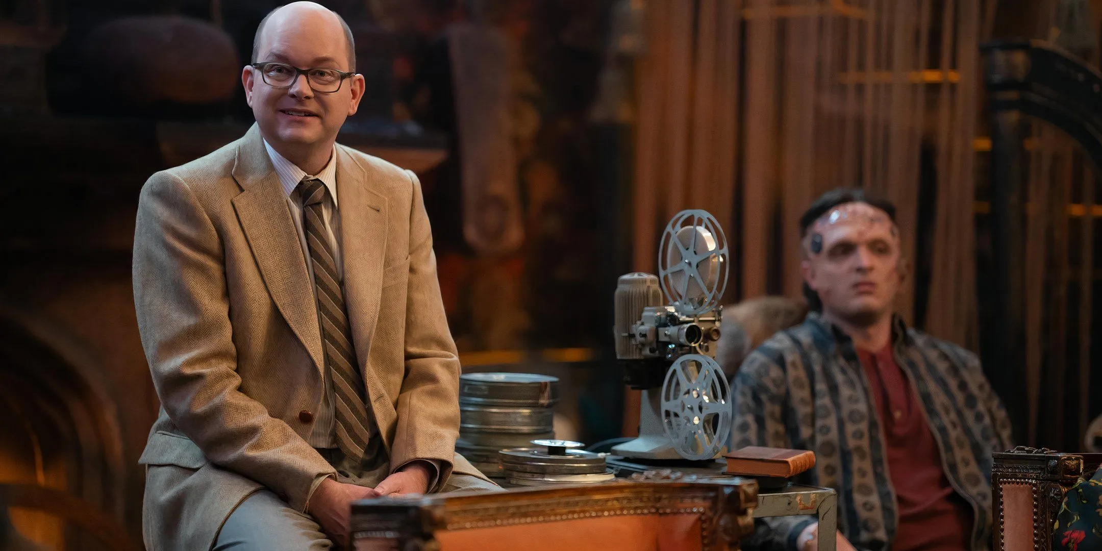 Mark Proksch's Colin Robinson smiles beside a film projector in What We Do in the Shadows series finale