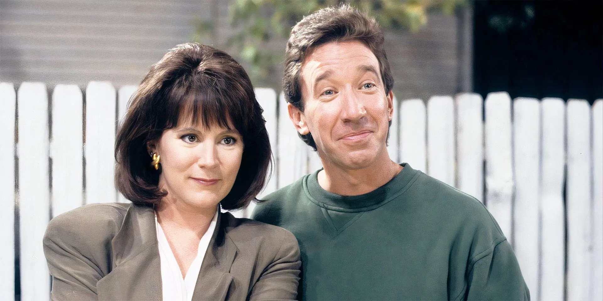 Patricia Richardson as Jill Taylor and Tim Allen as Tim Taylor smiling in their backyard in Home Improvement