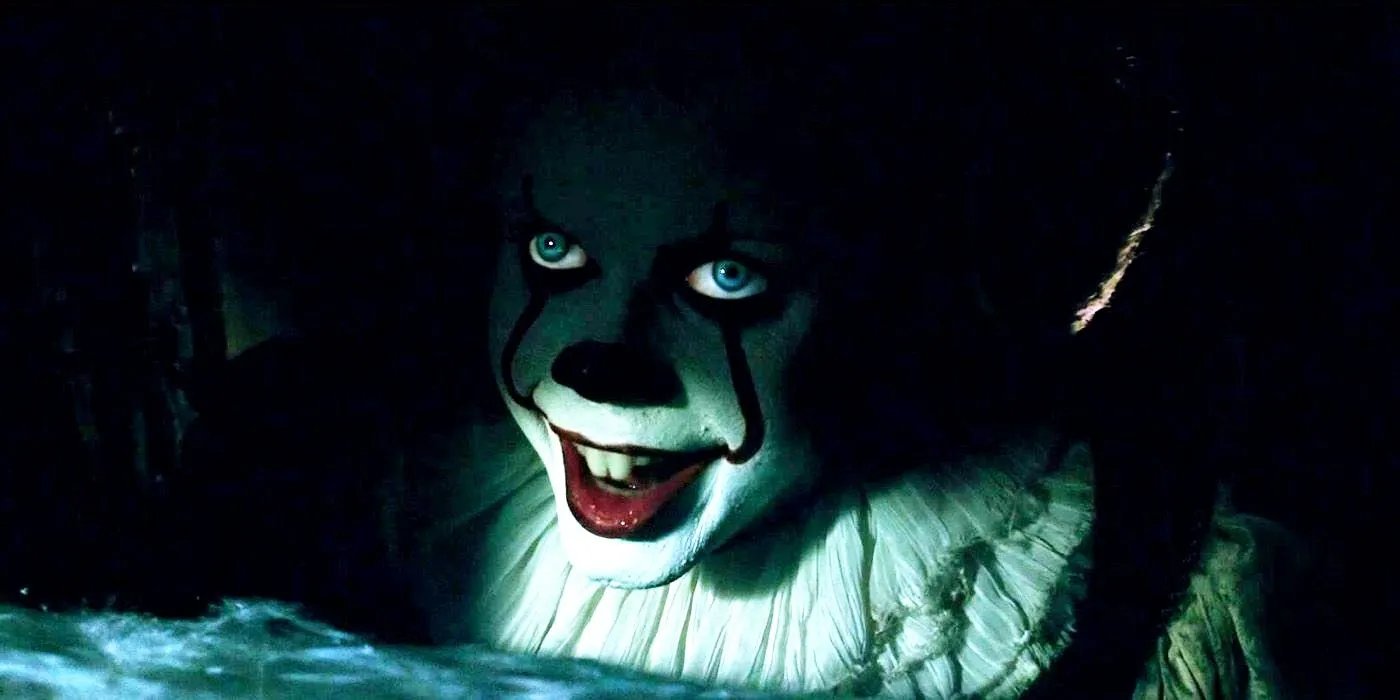 Pennywise de Bill Skarsgård sonriendo en las sombras del desagüe en la película de terror It de 2017