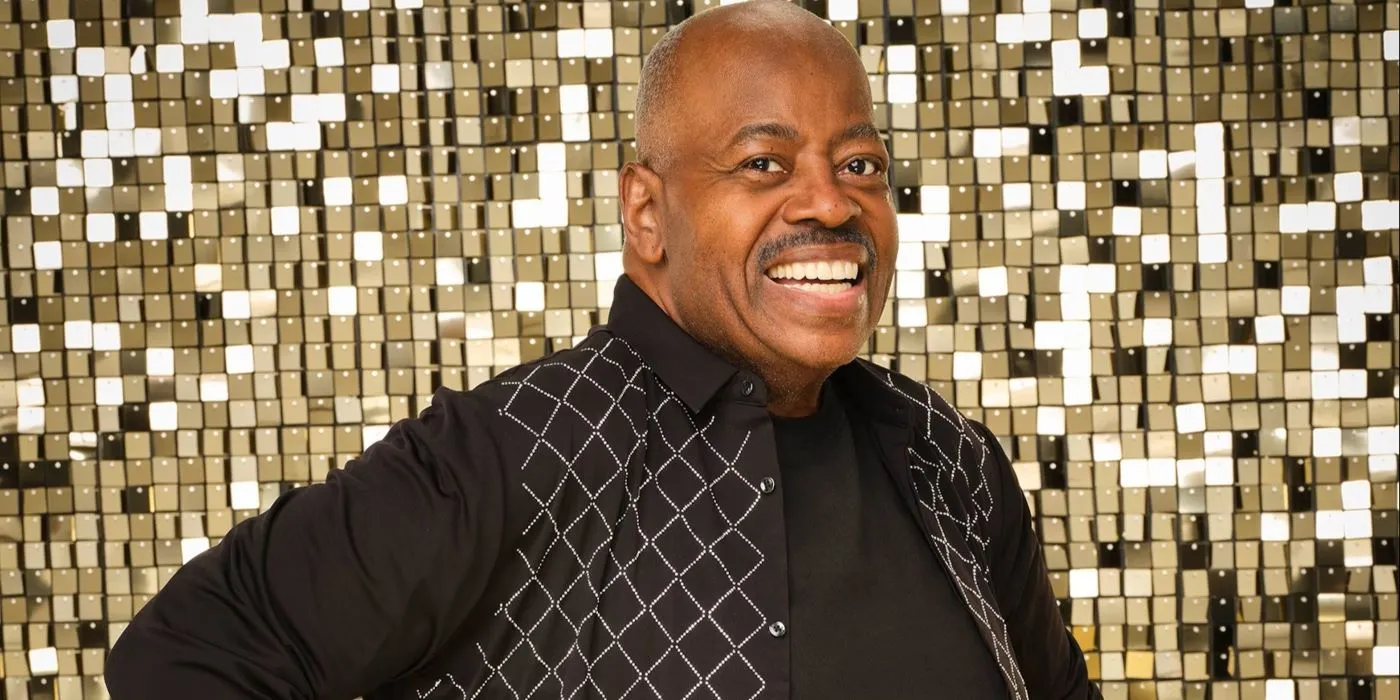 Reginald VelJohnson pour Dancing with the Stars portant une tenue de danse de salon noire souriant brillamment