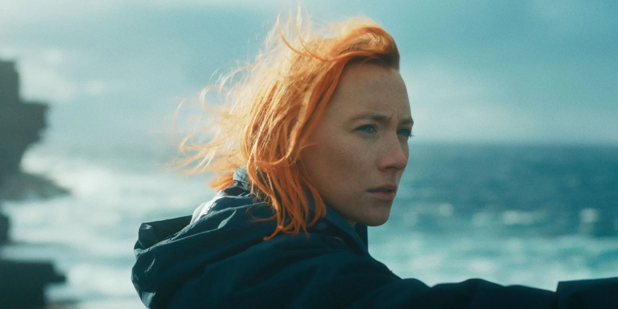 Saoirse Ronan au bord de la mer regardant sur le côté dans The Outrun