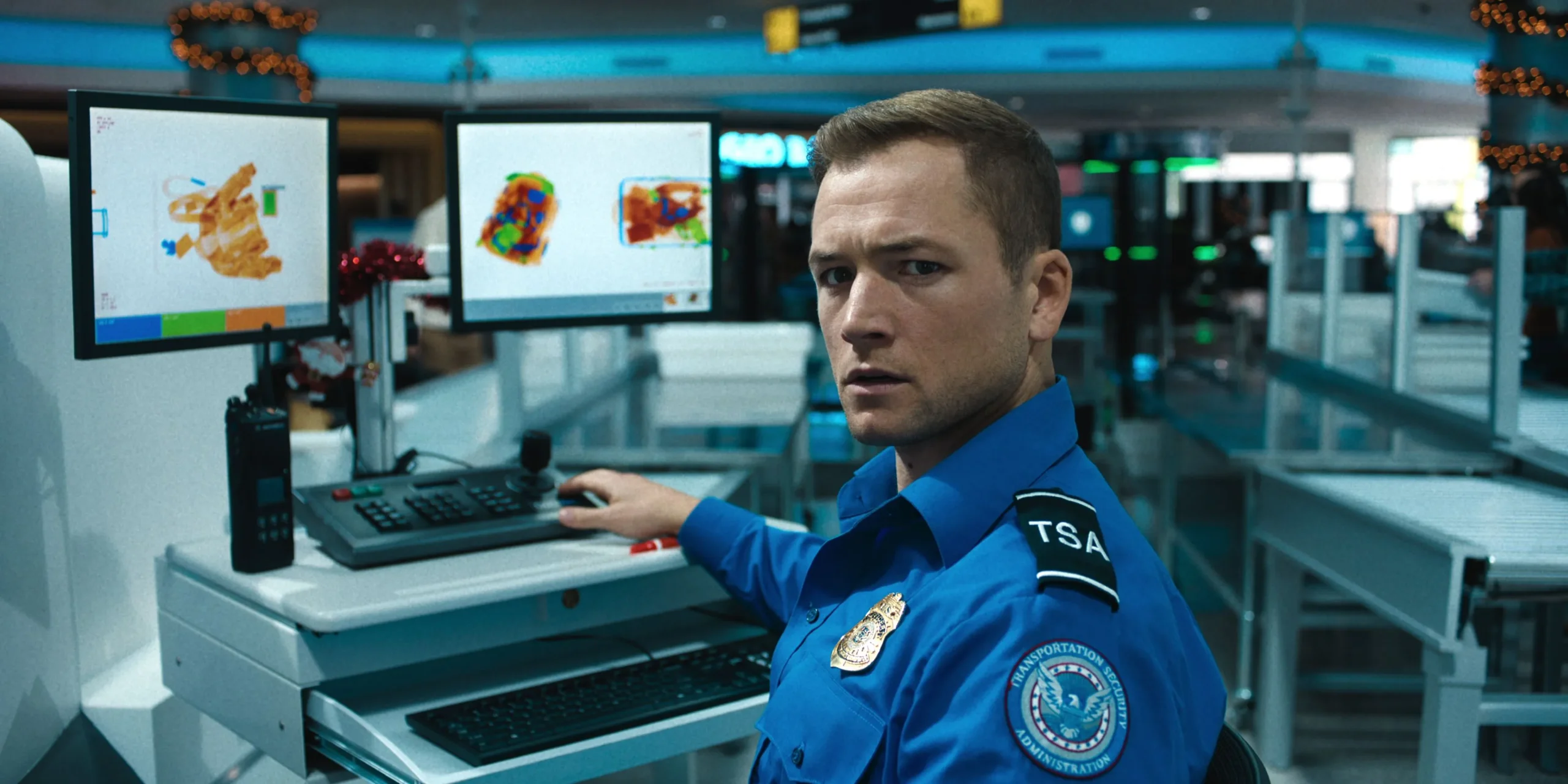 Taron Egerton in a TSA uniform looking concerned