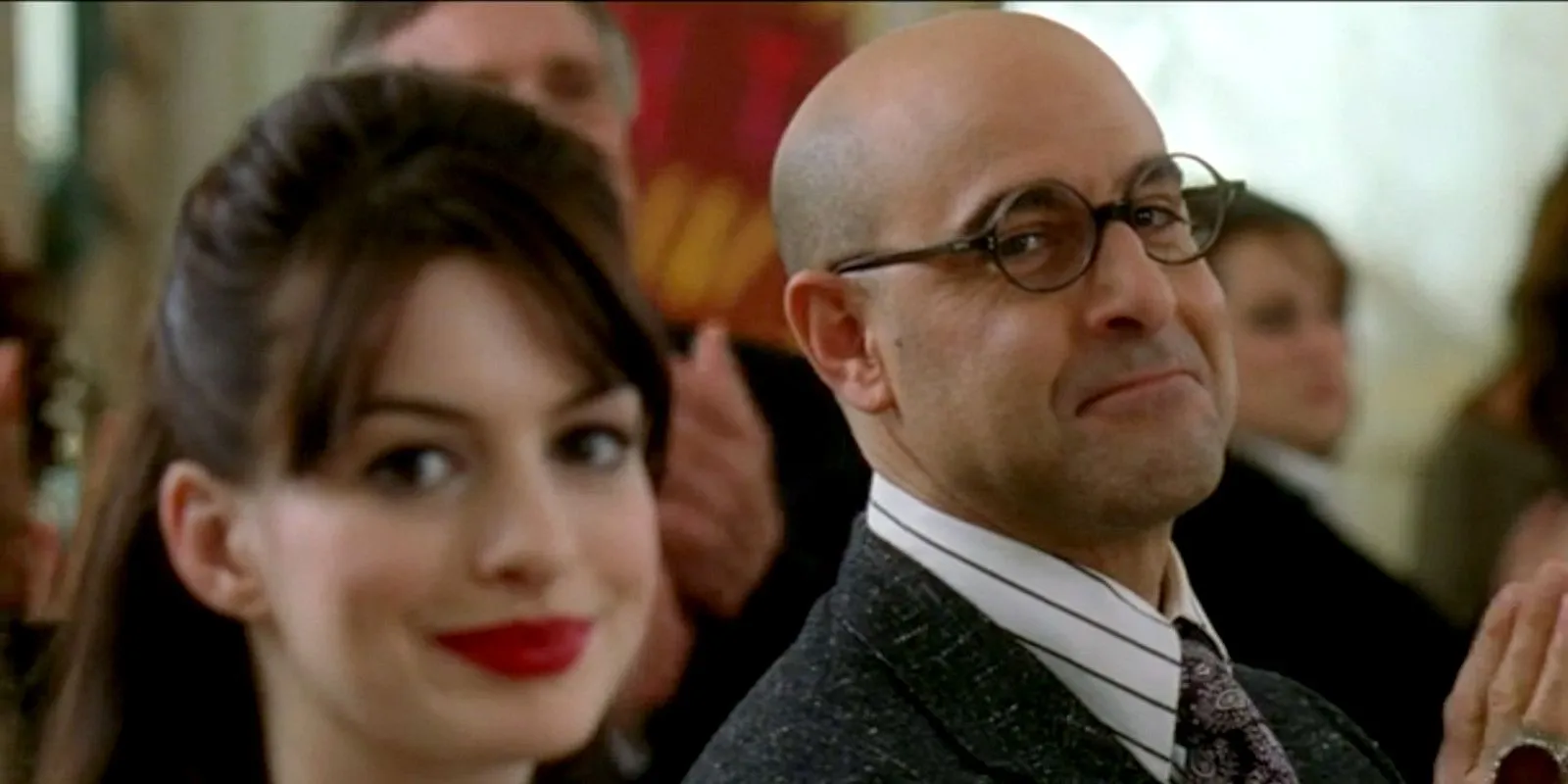 Anne Hathaway e Stanley Tucci sorrindo em O Diabo Veste Prada