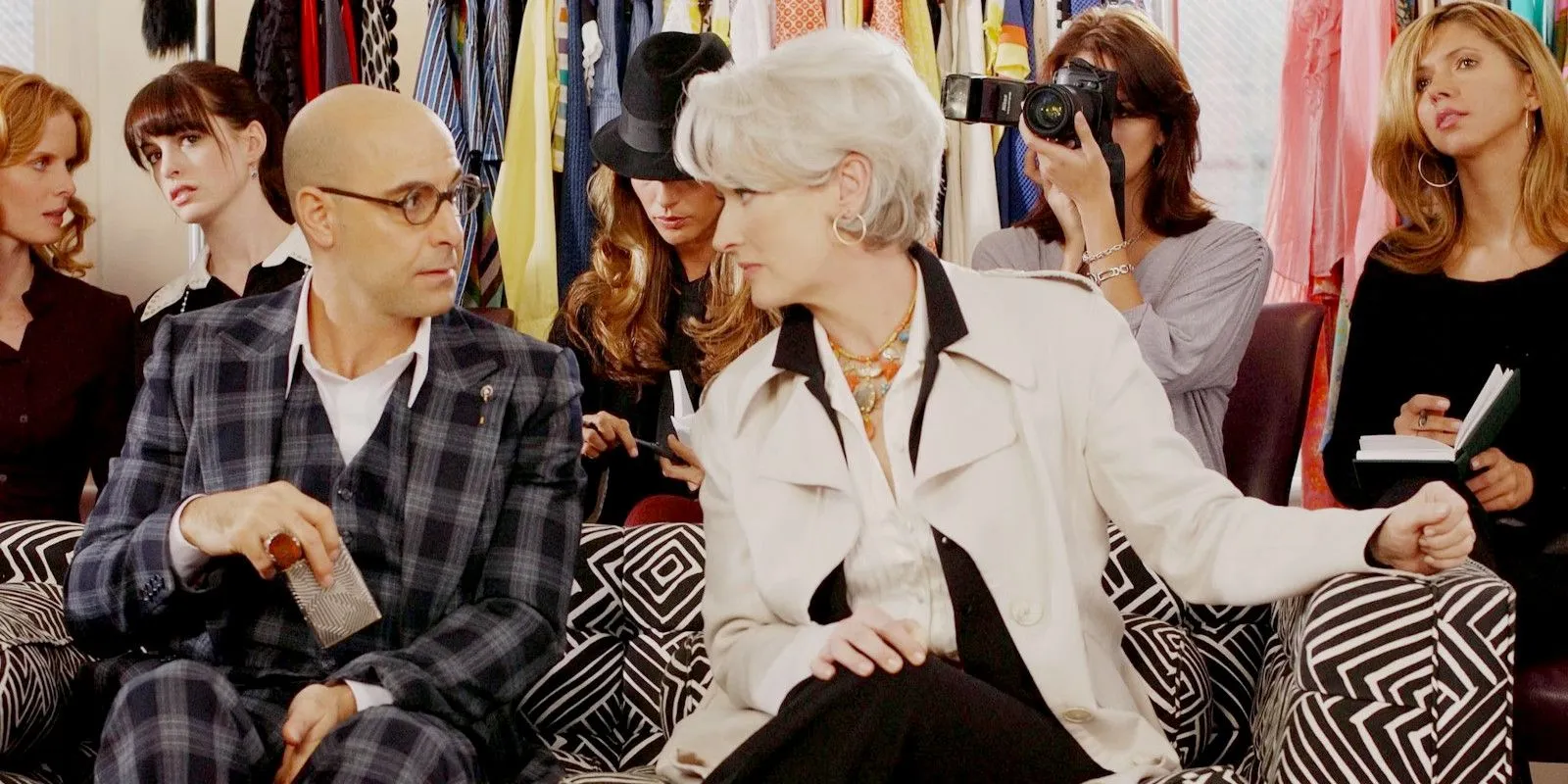 Nigel (Stanley Tucci) e Miranda (Meryl Streep) sentados juntos durante um desfile de moda