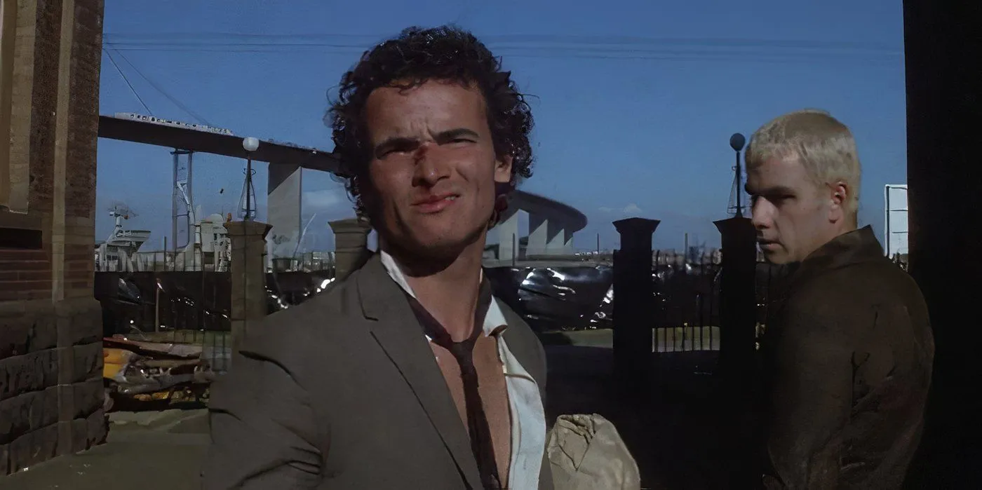 Tim Burns como Johnny the Boy usando uma gravata frouxa em Mad Max 1979