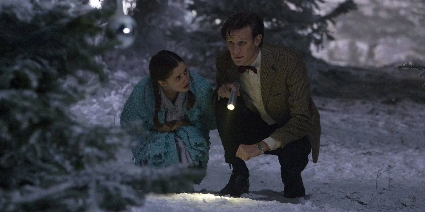 L'Undicesimo Dottore e Lily si inginocchiano nella neve con una torcia nello speciale di Natale del 2011 di Doctor Who