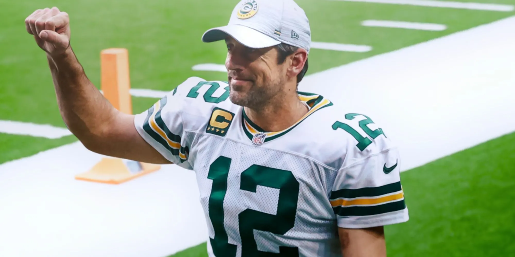 Aaron Rodgers dans le rôle d'un Packer de Green Bay souriant avec son poing en l'air dans Aaron Rodgers : Enigma