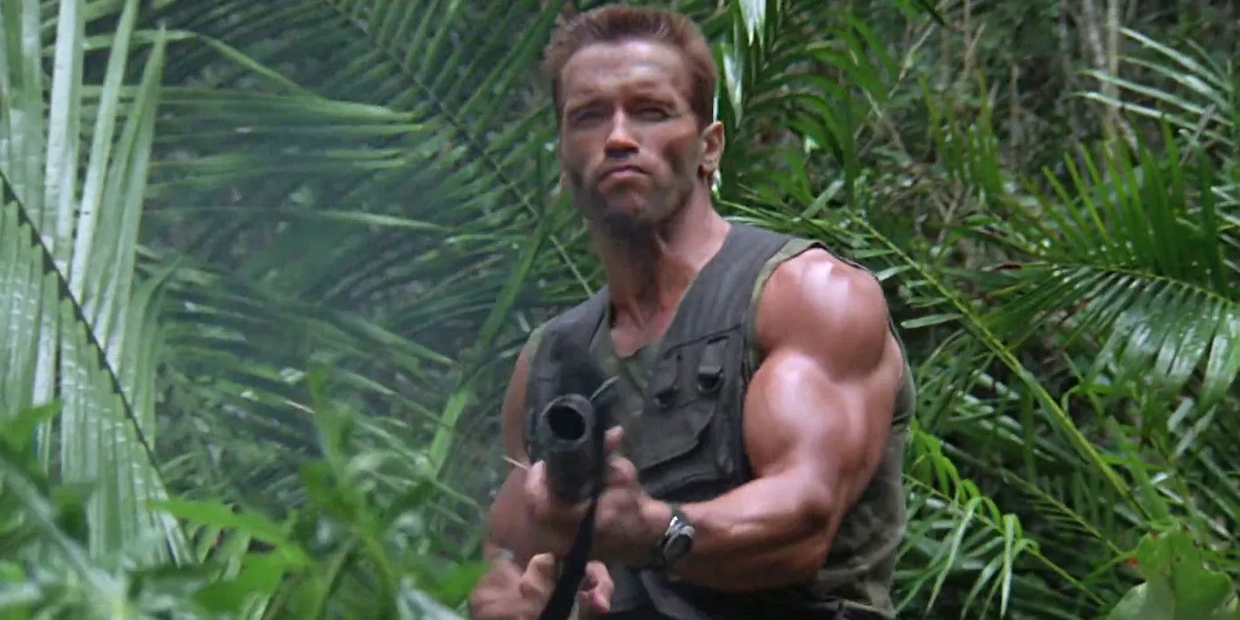 Arnold Schwarzenegger als Dutch in „Predator“ zielt mit einem Maschinengewehr, während er vor einem Dschungellaub steht