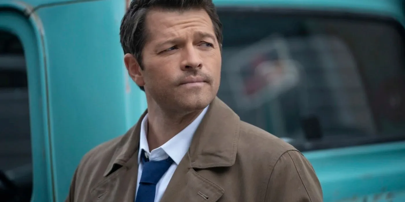 Castiel se ve serio parado frente a un auto azul en Supernatural