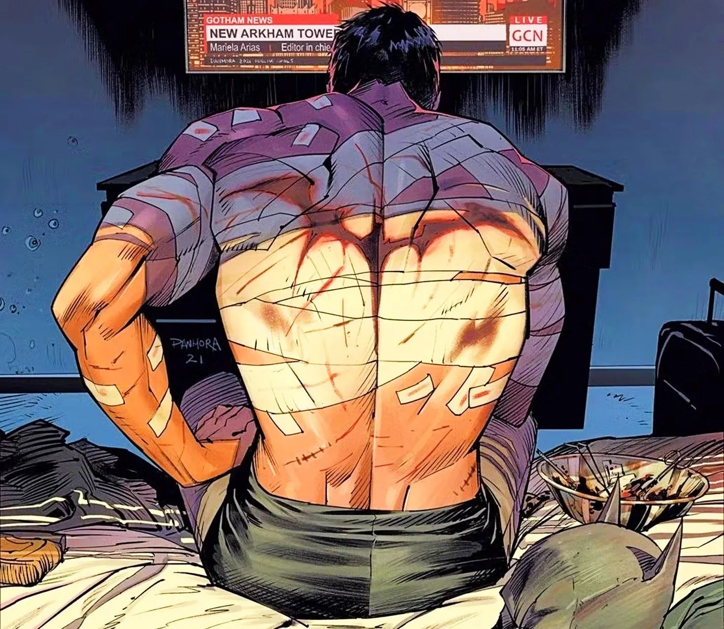 Bruce Wayne sitting watching TV with the Batman symbol on his back