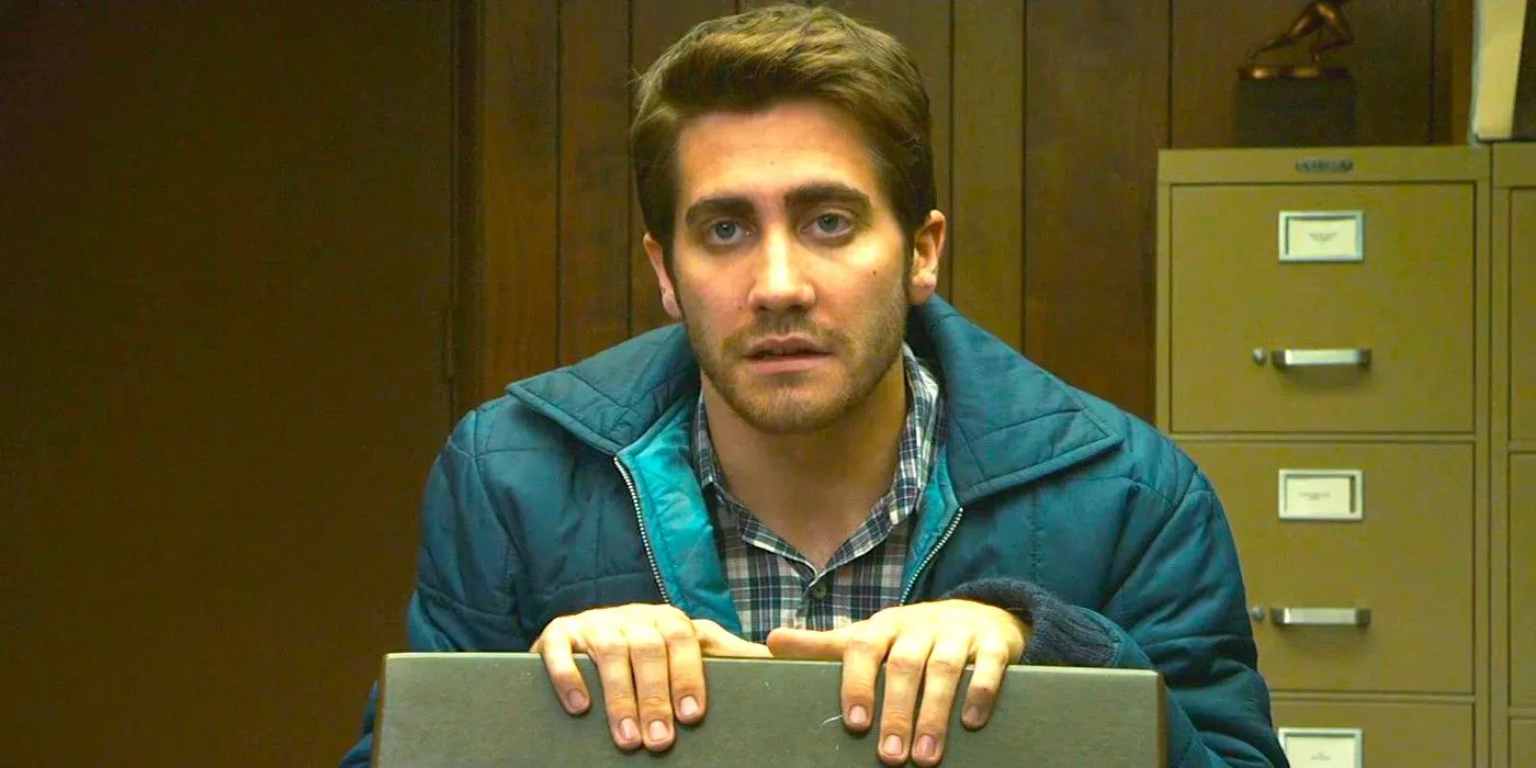 傑克·吉倫哈爾 (Jake Gyllenhaal) 穿著藍色夾克，坐在辦公室的椅子上，穿著十二生肖，看起來乾淨利落